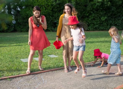 A joyous family experience in a lush Portugal park, featuring playful activities between young girls and adults.